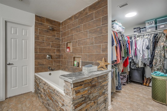 bathroom featuring tiled shower / bath combo and a textured ceiling