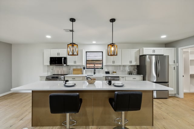 kitchen featuring stainless steel appliances, white cabinetry, and a center island