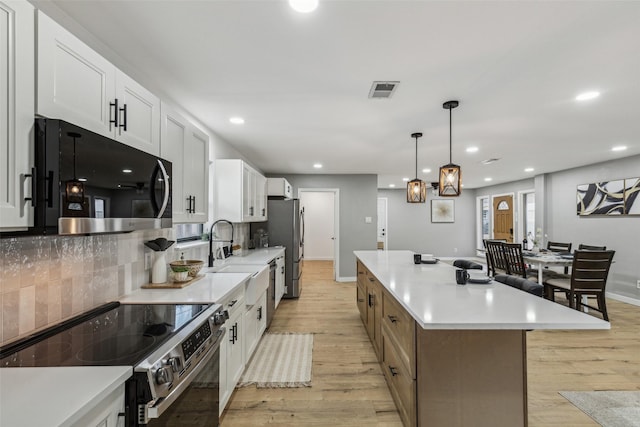 kitchen with stainless steel appliances, hanging light fixtures, white cabinets, and a spacious island