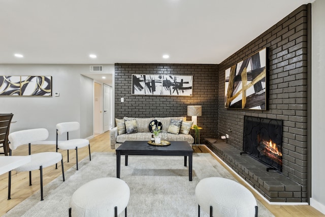 living room featuring a brick fireplace and light hardwood / wood-style flooring