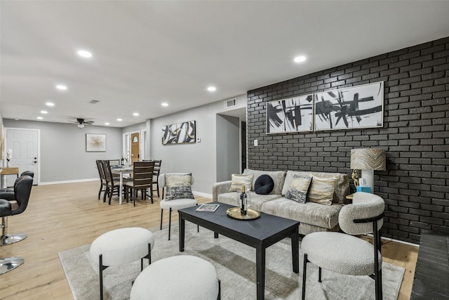 living room with brick wall, ceiling fan, and light hardwood / wood-style flooring