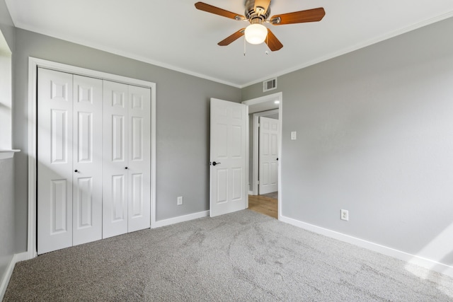 unfurnished bedroom with crown molding, carpet floors, a closet, and ceiling fan