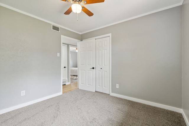 unfurnished bedroom featuring crown molding, light carpet, ceiling fan, and a closet