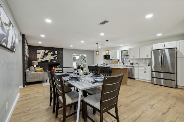 dining room featuring sink, a brick fireplace, and light wood-type flooring