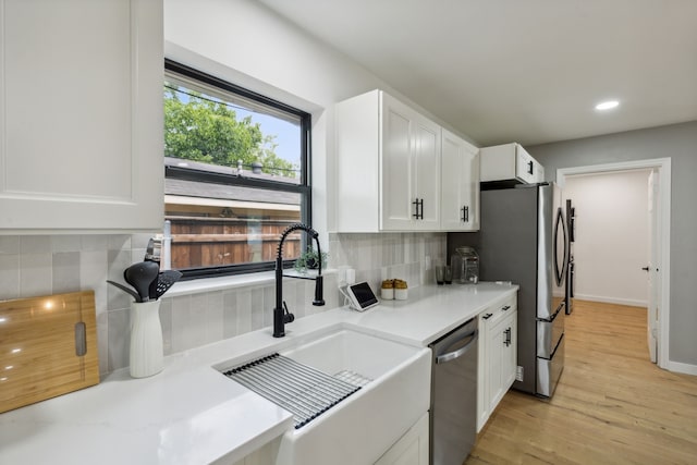 kitchen featuring sink, appliances with stainless steel finishes, white cabinetry, decorative backsplash, and light wood-type flooring