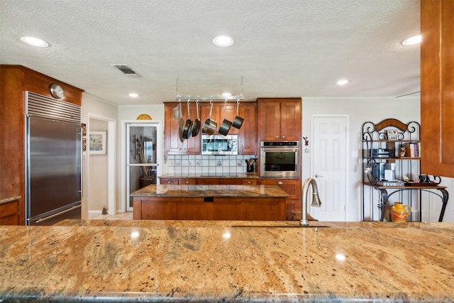 kitchen with backsplash, sink, dark stone countertops, a textured ceiling, and appliances with stainless steel finishes