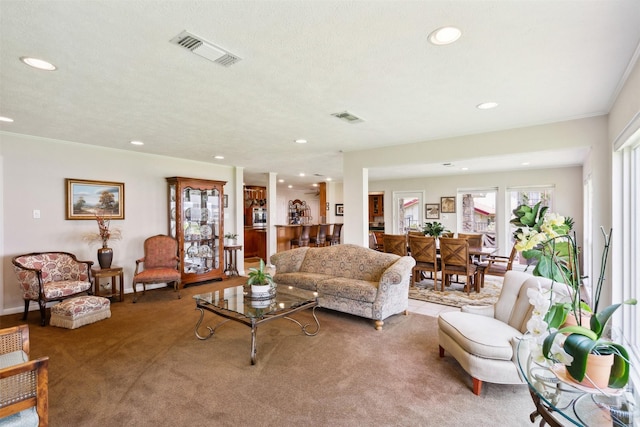 living room with carpet, a textured ceiling, and ornamental molding