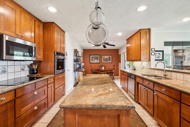 kitchen with light stone countertops, backsplash, stainless steel appliances, sink, and a kitchen island