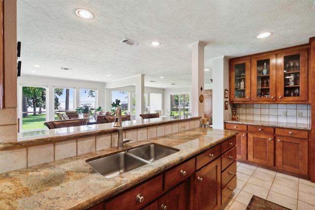 kitchen featuring a textured ceiling, light stone counters, sink, and tasteful backsplash