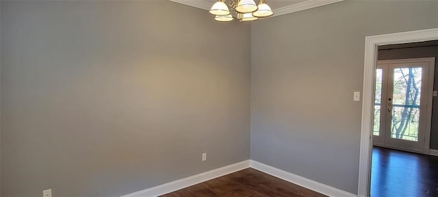 spare room featuring dark hardwood / wood-style floors, a chandelier, and ornamental molding