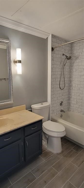 full bathroom with tiled shower / bath, toilet, crown molding, and vanity