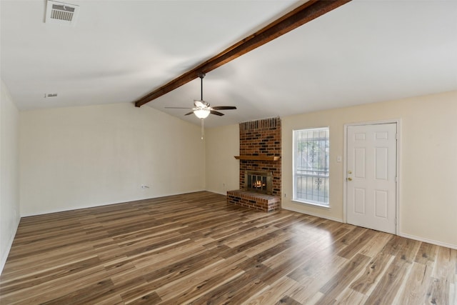 unfurnished living room with hardwood / wood-style floors, ceiling fan, lofted ceiling with beams, and a brick fireplace