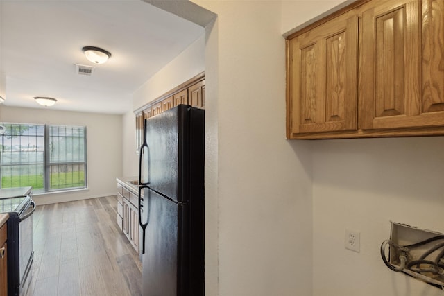 kitchen featuring light wood-type flooring, electric range, and black fridge