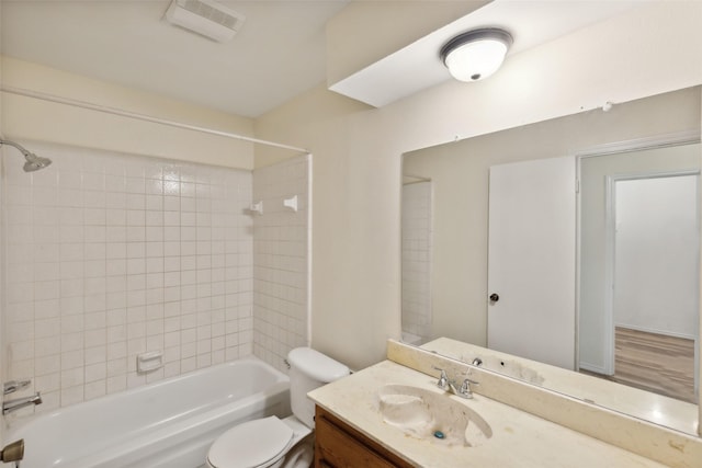 full bathroom featuring tiled shower / bath, vanity, and toilet