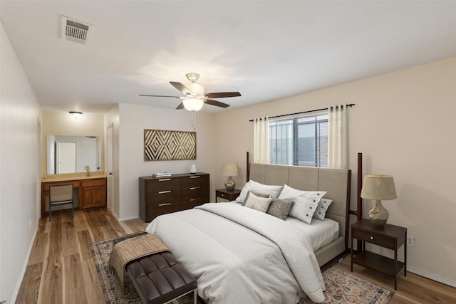 bedroom with ensuite bath, light hardwood / wood-style flooring, and ceiling fan