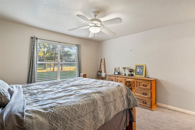 carpeted bedroom featuring ceiling fan and a textured ceiling