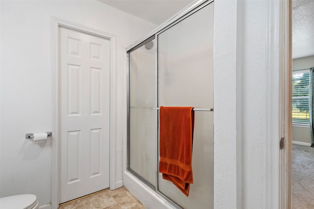 bathroom featuring toilet and an enclosed shower