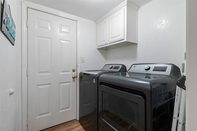 clothes washing area with hardwood / wood-style flooring, cabinets, and independent washer and dryer