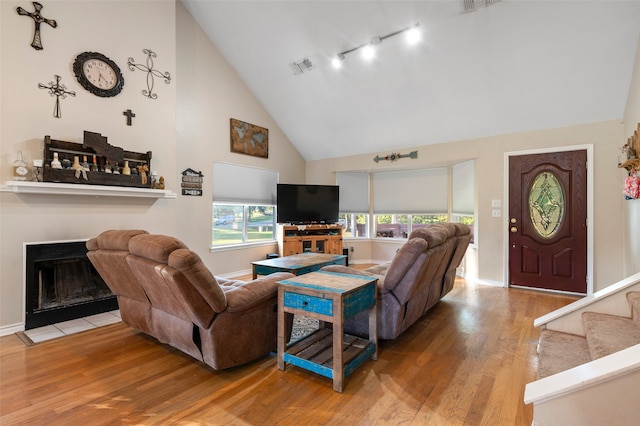 living room with hardwood / wood-style flooring, high vaulted ceiling, and track lighting