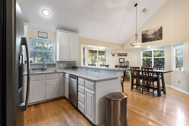 kitchen featuring white cabinets, kitchen peninsula, stainless steel appliances, and light hardwood / wood-style flooring