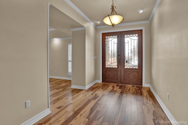 foyer entrance featuring crown molding, french doors, and light wood-type flooring