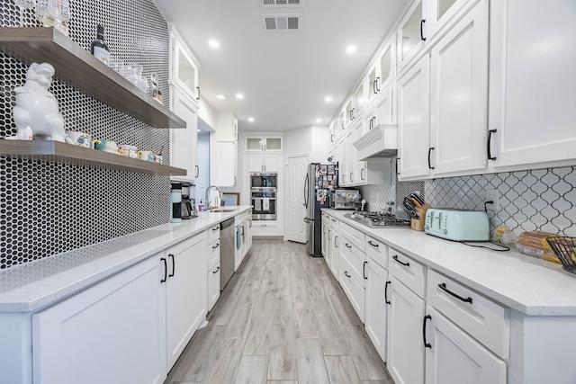 kitchen with a sink, visible vents, appliances with stainless steel finishes, decorative backsplash, and open shelves