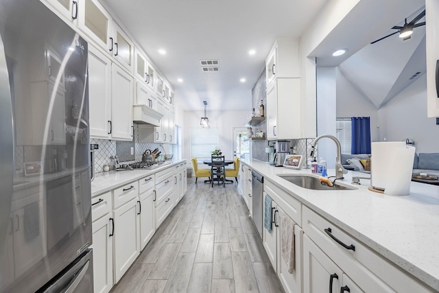 kitchen with visible vents, decorative backsplash, stainless steel appliances, white cabinetry, and a sink