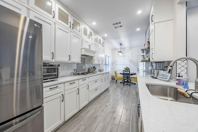 kitchen with visible vents, appliances with stainless steel finishes, a sink, white cabinetry, and backsplash