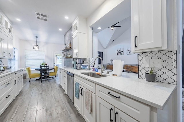 kitchen featuring lofted ceiling, white cabinets, a sink, and stainless steel dishwasher