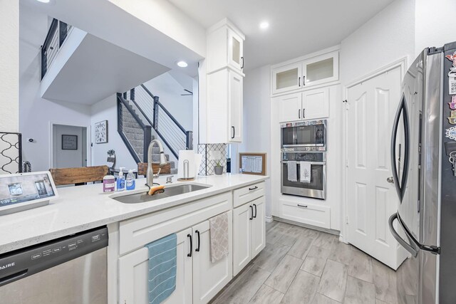 kitchen featuring white cabinetry, light hardwood / wood-style flooring, light stone counters, sink, and appliances with stainless steel finishes