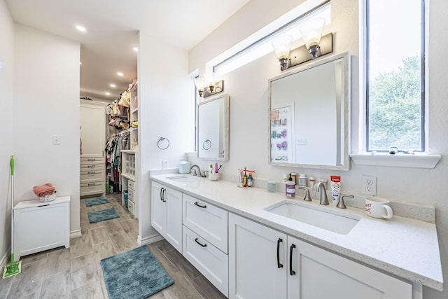 full bath featuring double vanity, a spacious closet, a sink, and wood finish floors