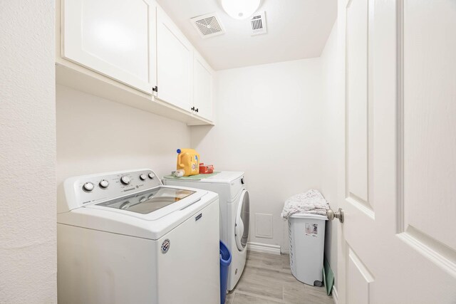 washroom featuring light wood-type flooring, cabinets, and washer and clothes dryer