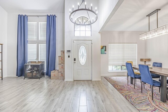 entryway with a towering ceiling, an inviting chandelier, and light hardwood / wood-style flooring