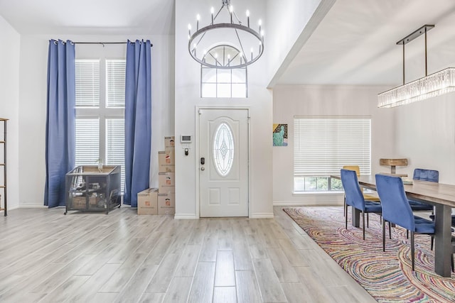 entryway with baseboards, a chandelier, and wood finished floors