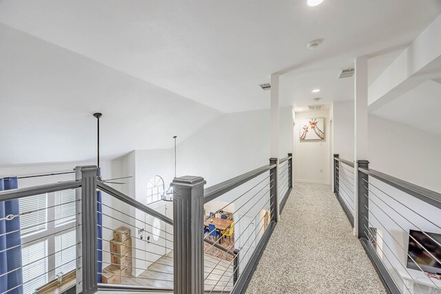 corridor with lofted ceiling and light colored carpet