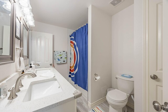 bathroom with wood-type flooring, toilet, and vanity