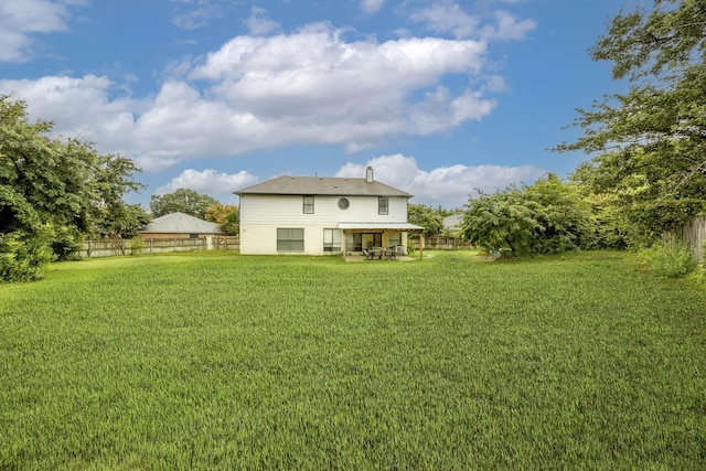 back of property with a chimney, fence, and a yard