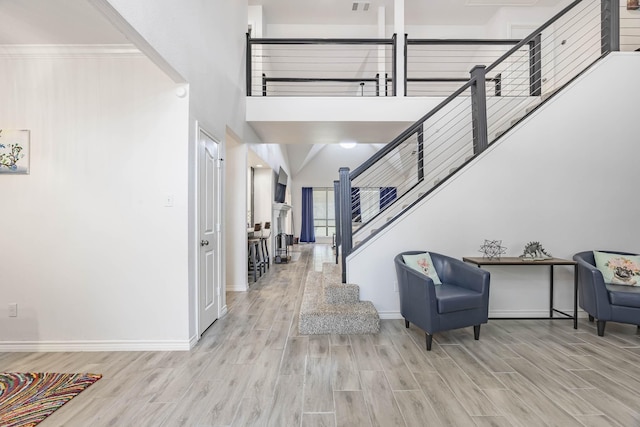 entrance foyer with a high ceiling, wood finished floors, visible vents, baseboards, and stairs