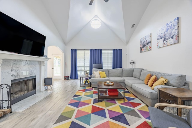 living room with a fireplace, visible vents, ceiling fan, wood finished floors, and high vaulted ceiling