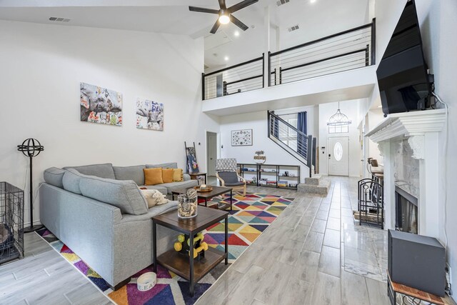 living room featuring hardwood / wood-style floors, high vaulted ceiling, ceiling fan, and a premium fireplace