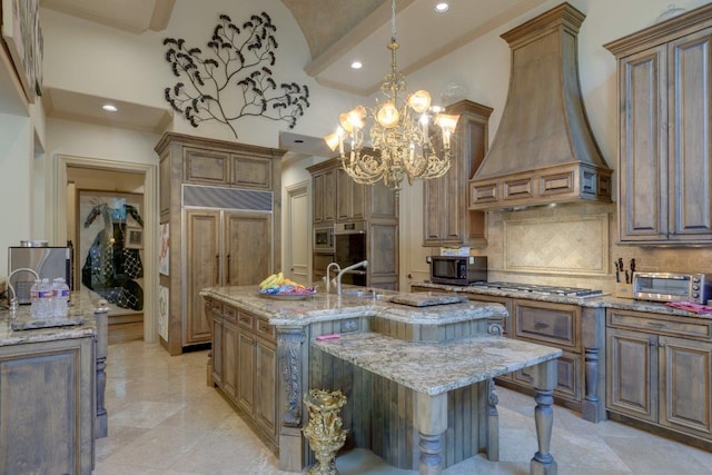 kitchen with premium range hood, a center island with sink, light stone countertops, tasteful backsplash, and stainless steel appliances