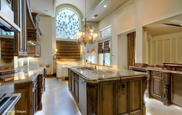 kitchen with decorative light fixtures, crown molding, a kitchen island with sink, and a high ceiling