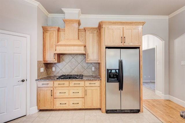 kitchen featuring crown molding, gas stovetop, stainless steel refrigerator with ice dispenser, stone countertops, and light brown cabinets