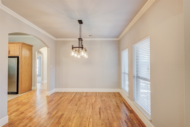 unfurnished dining area featuring ornamental molding, a chandelier, and light hardwood / wood-style floors