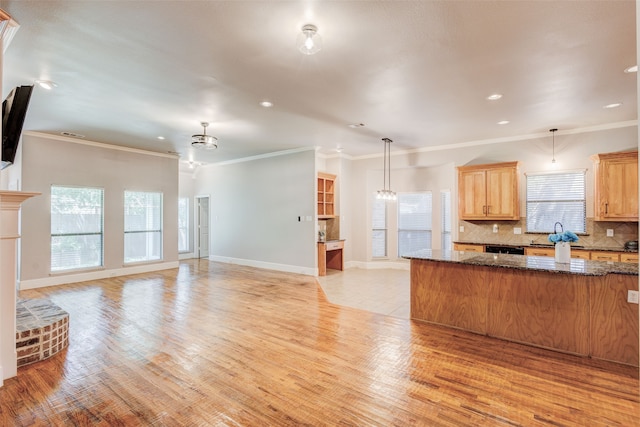 kitchen featuring dark stone countertops, decorative light fixtures, and light hardwood / wood-style floors