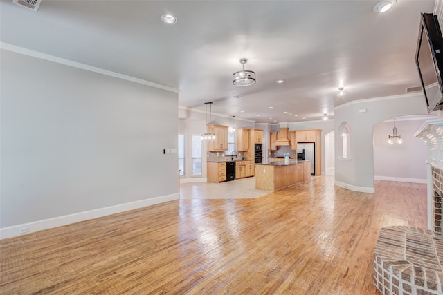 unfurnished living room featuring a fireplace, light wood-type flooring, ornamental molding, and a chandelier