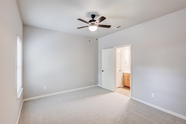 unfurnished bedroom with light carpet, connected bathroom, and ceiling fan