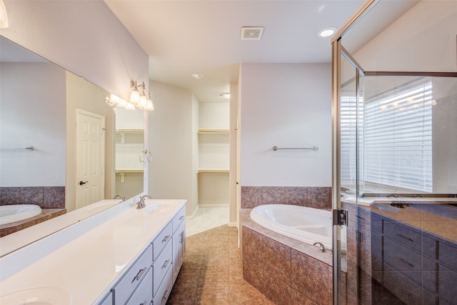 bathroom with tile patterned floors, a relaxing tiled tub, and vanity