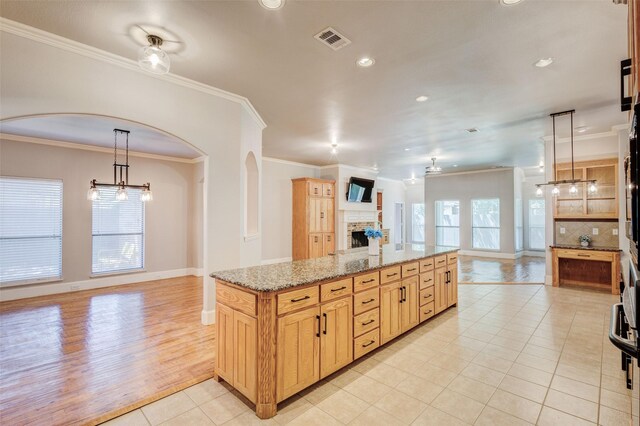 kitchen featuring light brown cabinetry, crown molding, light hardwood / wood-style flooring, decorative light fixtures, and a chandelier