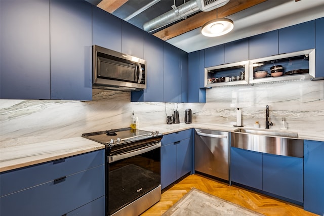 kitchen with blue cabinets, appliances with stainless steel finishes, sink, and light parquet flooring